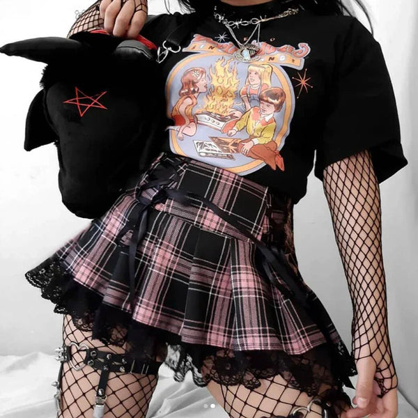 Person wearing a black t-shirt with a graphic design, plaid skirt, and fishnet stockings.