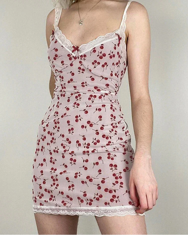 Woman wearing a lace-trimmed dress with cherry pattern on a plain background