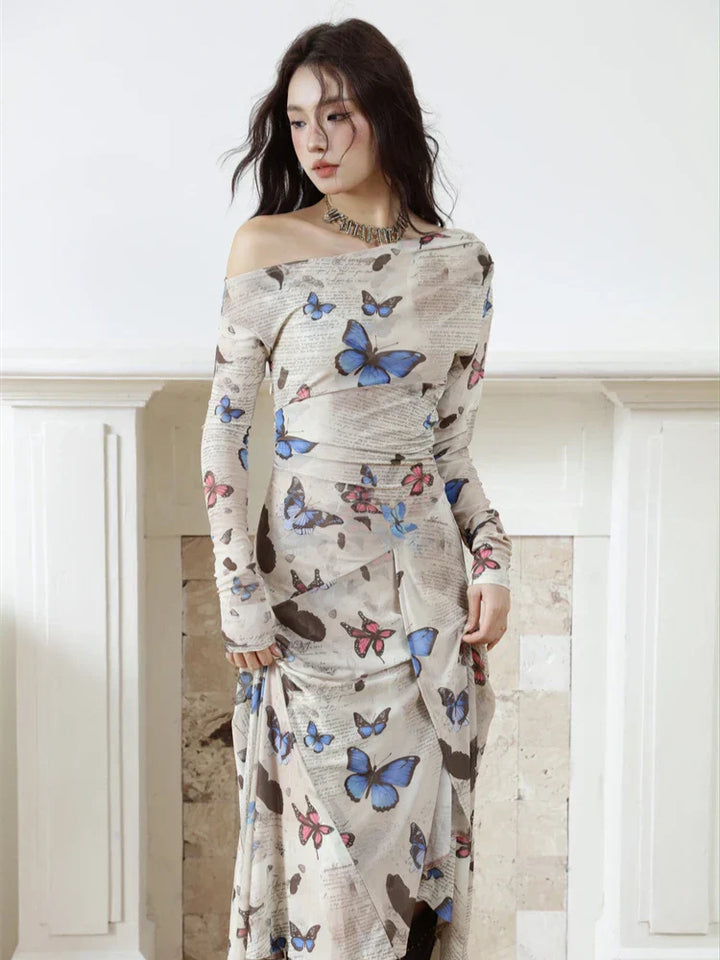 Woman wearing a long dress with butterfly pattern against a white wall.