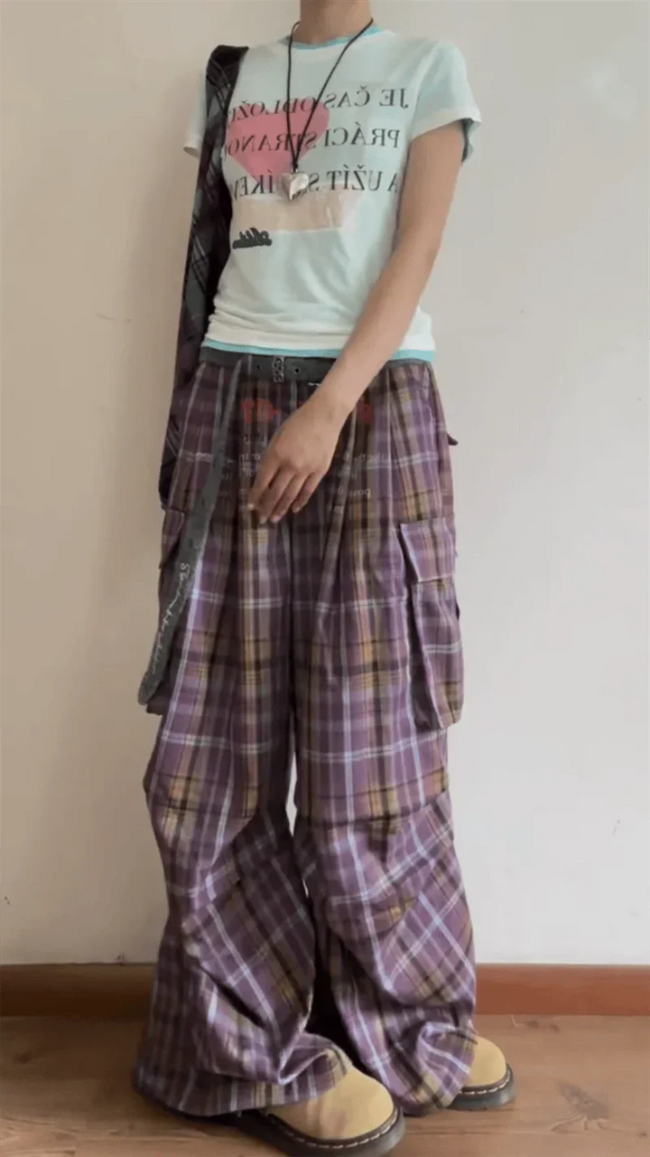 Person wearing a light-colored t-shirt and plaid pants with a plain background