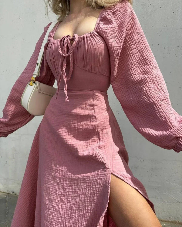 Person wearing a pink dress with long sleeves against a plain background
